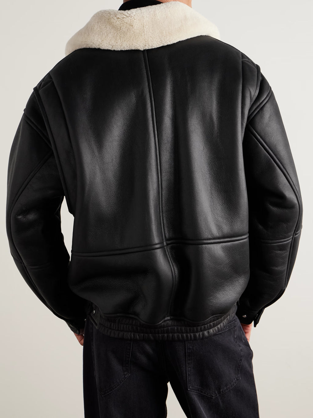 Black leather jacket with shearling collar on a neutral background